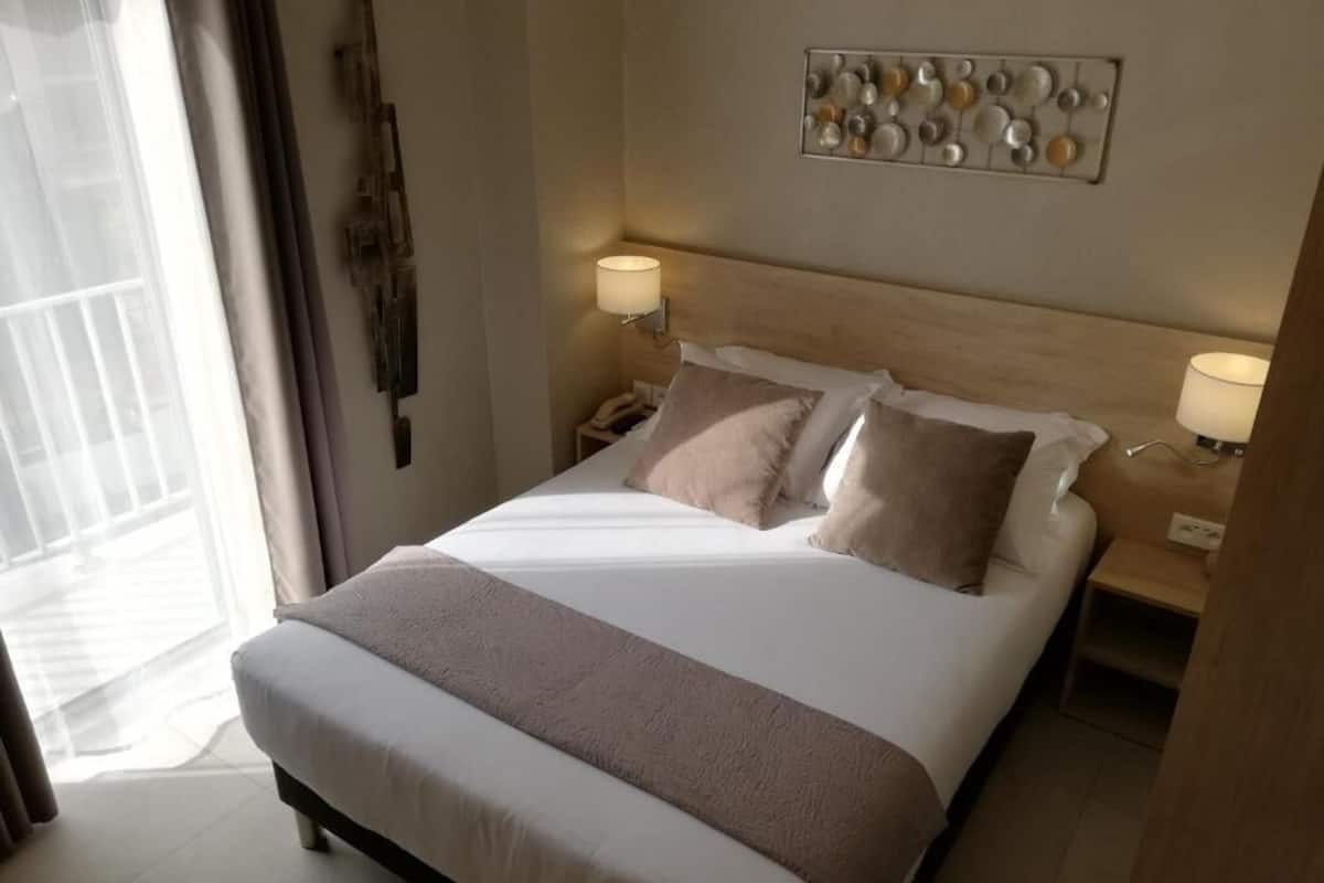 Ett hotellrum med en stor säng, två sänglampor, ett konstverk på väggen och utsikt över omgivningarna.