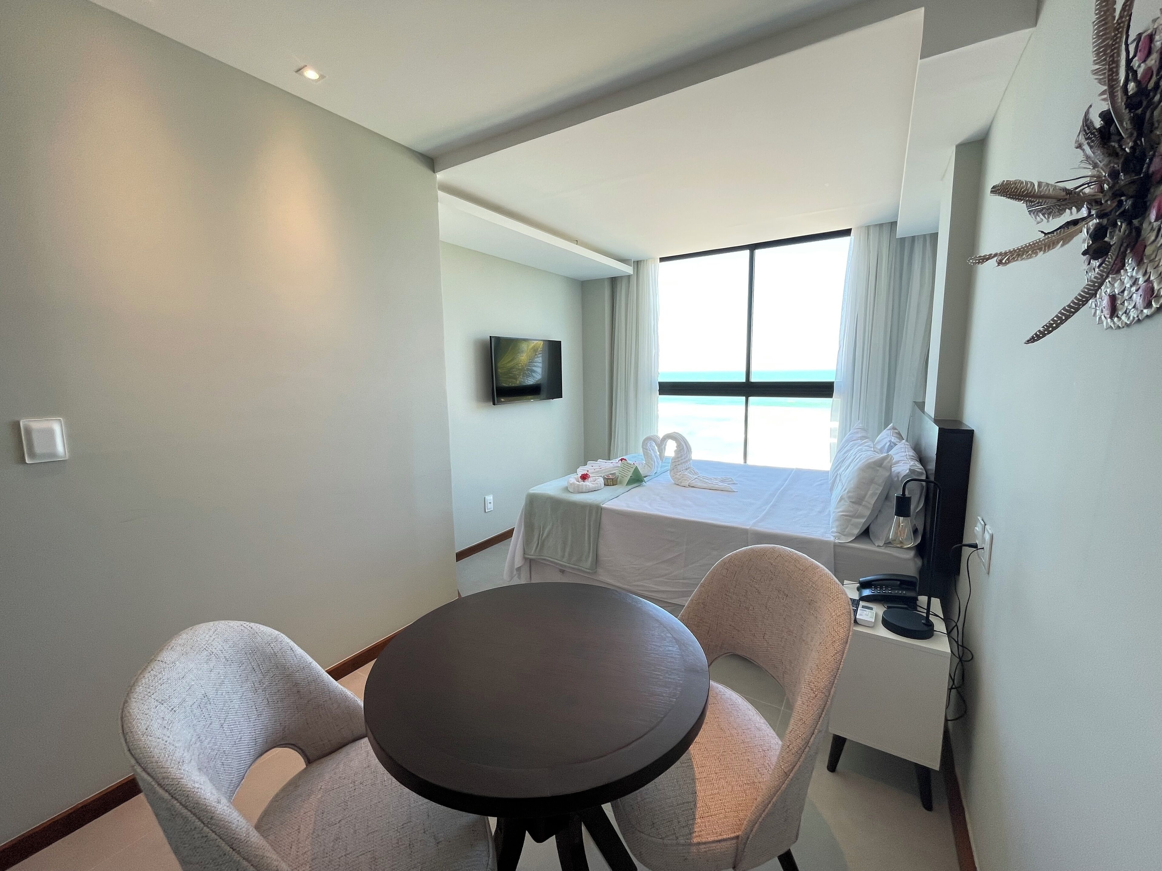 A hotel room with a bed, a TV, a table, and two chairs.