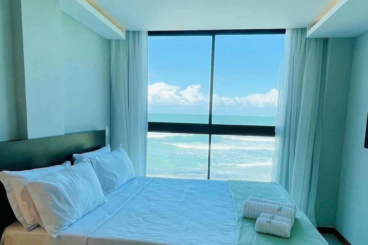 Une chambre d’hôtel avec un grand lit, une table de chevet et une vue sur l’océan.