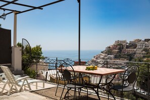 A terrace with a table and chairs overlooking a coastal town.