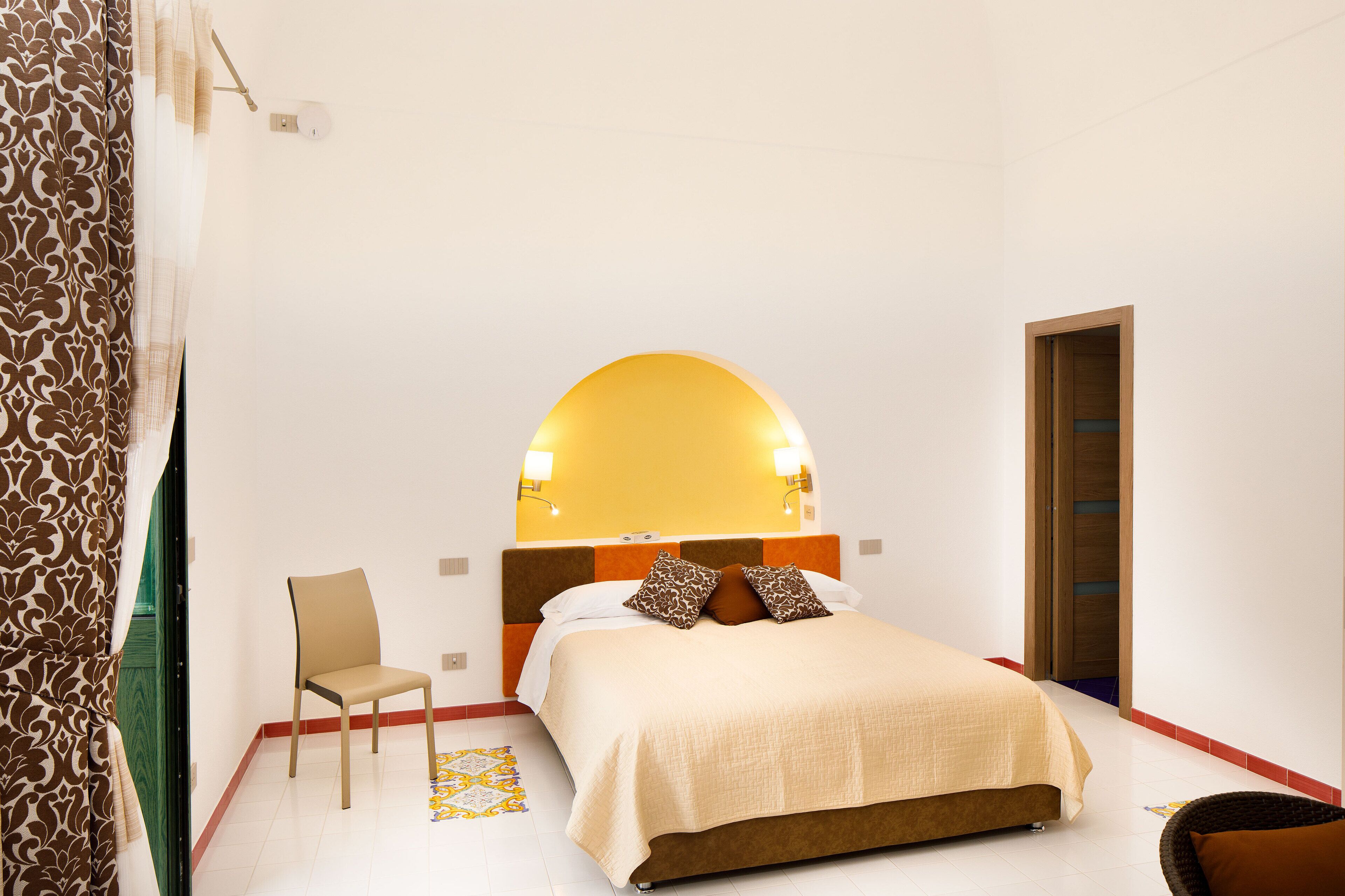 Een slaapkamer met een bed, een stoel, een spiegel en een deur.