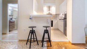 Een moderne keuken met twee krukken, een aanrechtblad en een zicht op de aangrenzende badkamer.