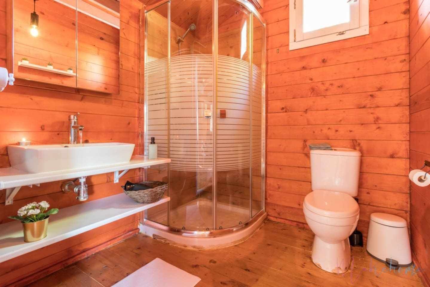 Puisesta mökistä löytyy kylpyhuone, jossa on lasiseinällä varustettu suihku, peilillä varustettu pesuallas ja wc.