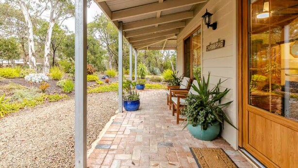 A covered outdoor area with a brick pathway, wooden benches, and potted plants. - CARNBRAE BnB Cosy and relaxing couples getaway! (Macclesfield)
