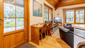 A cozy kitchen with wooden cabinets, a dining area with chairs, a sofa, and a television. - CARNBRAE BnB Cosy and relaxing couples getaway! (Macclesfield)