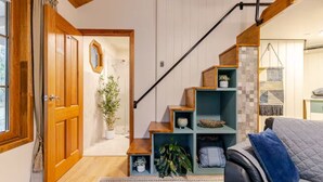 A wooden staircase with built-in shelves, a potted plant, and a patterned rug in a modern interior space. - CARNBRAE BnB Cosy and relaxing couples getaway! (Macclesfield)