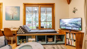 A cozy living room with a wooden bench, a television, and a bookshelf. - CARNBRAE BnB Cosy and relaxing couples getaway! (Macclesfield)