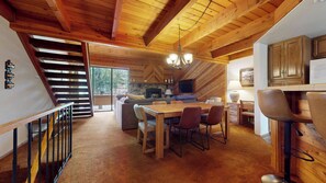 A spacious kitchen with a dining area, wooden ceiling beams, and a stone fireplace. - Pet-Friendly, Large & Rustic, Gas Grill. Pool, Hot Tub & Tennis Court On-site (Mammoth Lakes)
