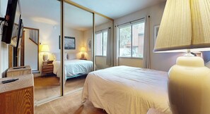 A hotel room with a bed, bedside lamps, a mirror, a dresser, and a window with blinds. - Pet-Friendly, Large & Rustic, Gas Grill. Pool, Hot Tub & Tennis Court On-site (Mammoth Lakes)