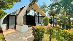 A modern building with a unique curved roof structure, a glass door entrance, and a number '303' sign. - Lucca Resort & Residence (Bandengan)