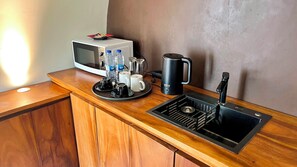 A kitchenette with a microwave, coffee maker, and sink. - Lucca Resort & Residence (Bandengan)