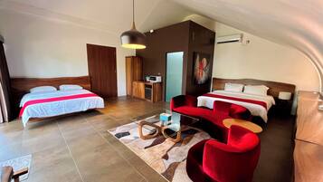 Ein Hotelzimmer mit zwei Betten, einem roten Sofa, einem kleinen Tisch und einer Deckenleuchte.