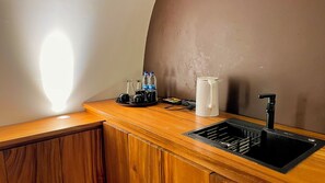 A kitchenette with a sink, a coffee maker, and a water dispenser.