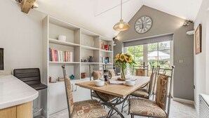 Ein Essbereich mit einem Holztisch, gemusterten Stühlen und einer Bücherwand mit Büchern und Dekoration.