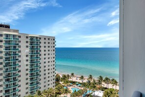 Ein hoch aufragendes Hotel mit Blick auf einen Strand, einen Pool und Palmen.