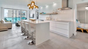 A modern kitchen with a central island, bar stools, and a hanging light fixture. - Beach front 2/1.5 luxuriously renovated space NEW! Rare find ... (Hollywood)