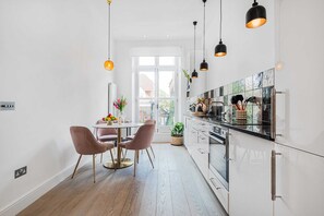 A modern kitchen with white cabinets, a black countertop, and pendant lighting. - Lady on the Lane, 2 bed Primrose Hill - by Out of Office Lifestyle (London)