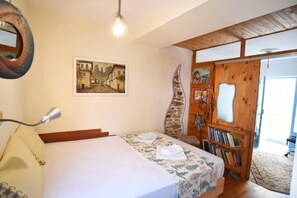 Un dormitorio con una cama, una puerta de madera, una estantería y un cuadro en la pared.