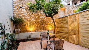 Un patio con pared de piedra, cerca de madera y una mesa con sillas.