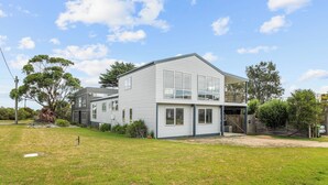 Moderni, kaksikerroksinen talo, jossa on suuri etupiha, autotalli ja parveke.