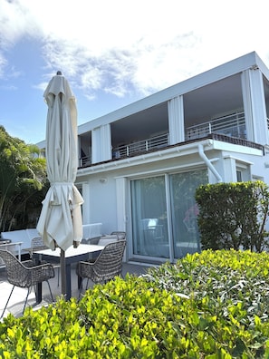 A modern building with a balcony, outdoor seating, and greenery. - Lovely 2 bedrooms apartment, sea view and infinity pool (St Jean)