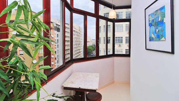 A corner room with a large window, a table, and a chair.