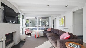 Ein modernes Wohnzimmer mit Kamin, einer großen Eckcouch und einem an der Wand befestigten Fernseher.