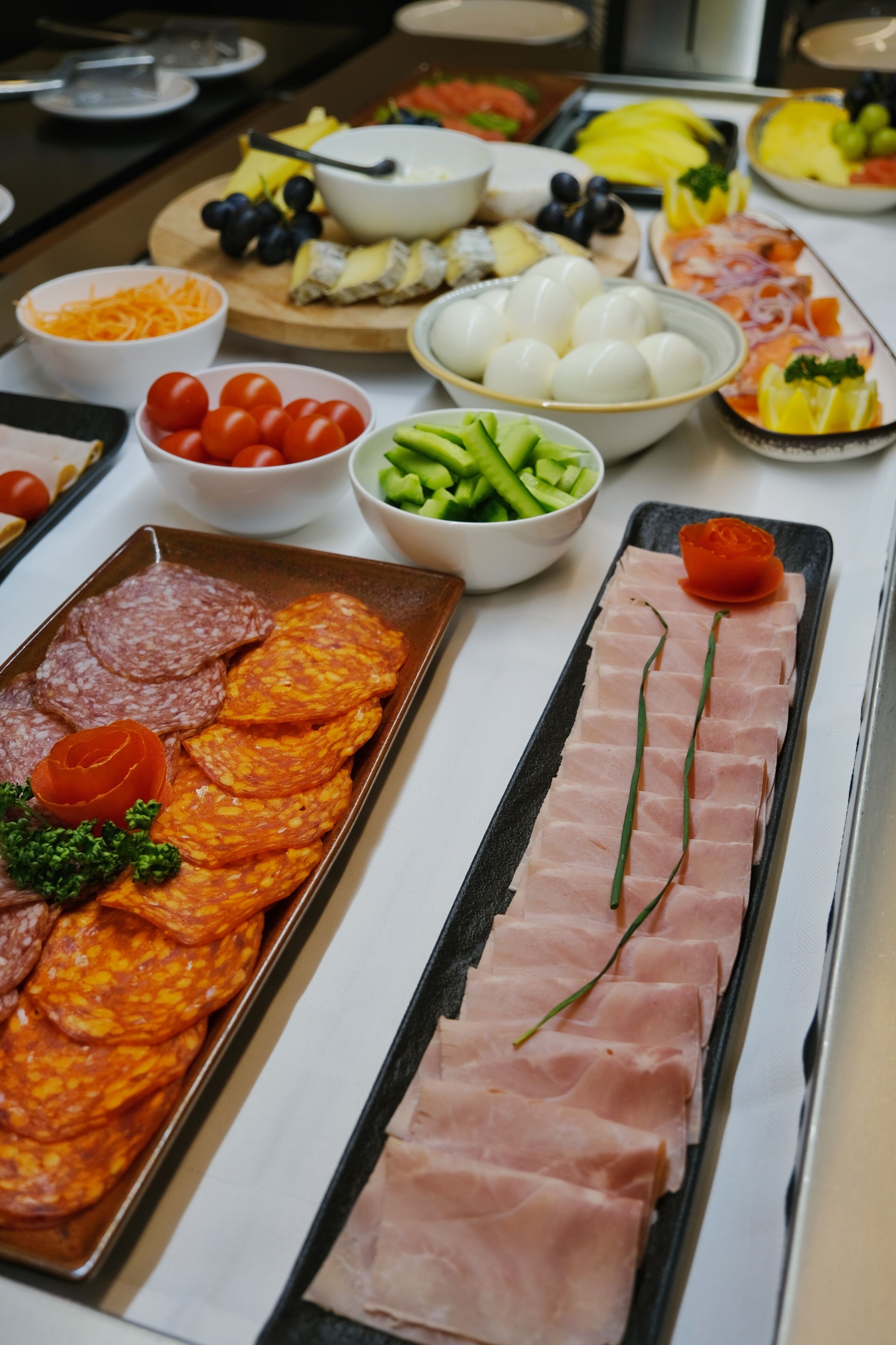 A buffet with various food items including meats, cheeses, and vegetables.