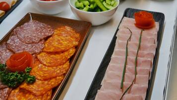 A buffet with various food items including meats, cheeses, and vegetables.