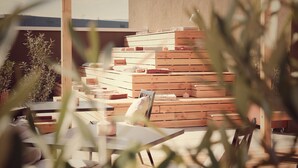 A wooden outdoor seating area with tables and chairs, surrounded by stacked wooden crates. - Afterwork Hotel (Etoy)