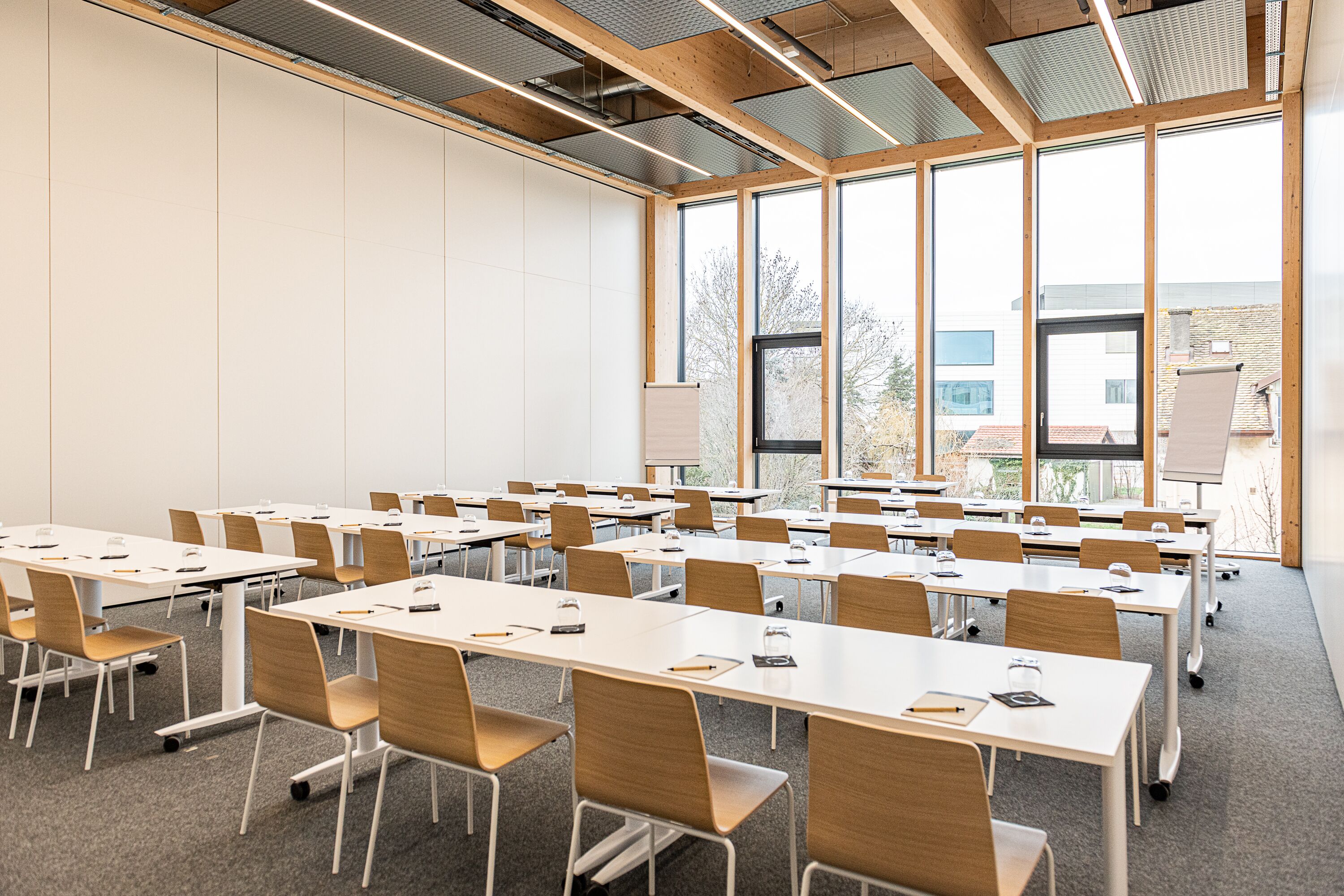 A conference room with multiple tables and chairs, large windows, and a whiteboard.