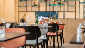 A restaurant interior with tables and chairs, shelves with decorative items, and a wooden accent wall.
