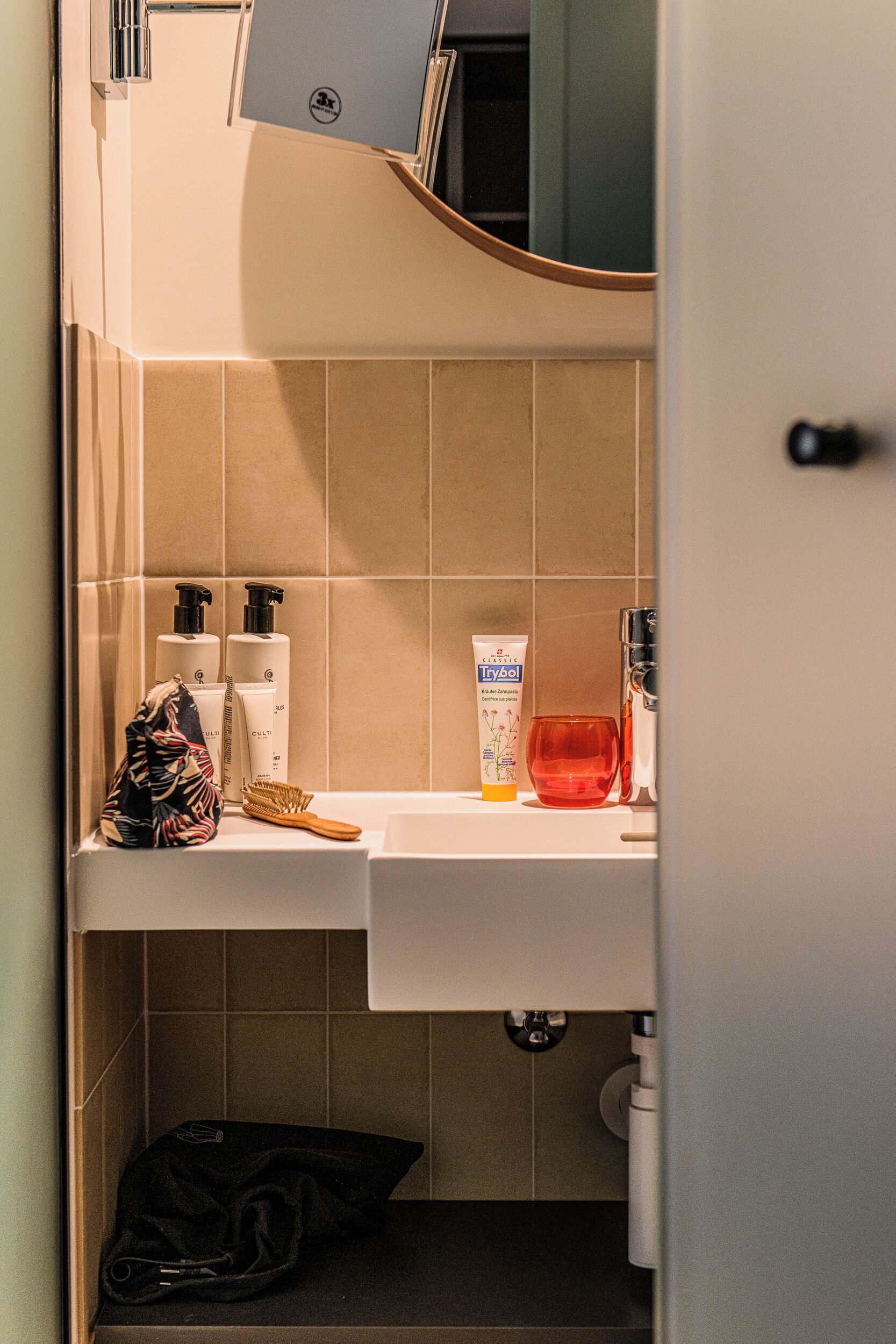 Un baño con lavamanos, artículos de aseo y espejo.