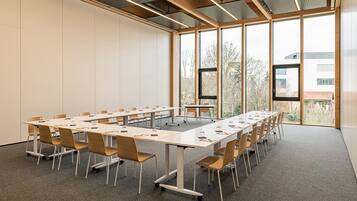 A conference room with a long table, chairs, and large windows.