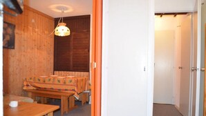 A room with a wooden table and benches, a hanging light fixture, and a white door. - 10m from ski slopes, 5th floor, view mountain, balcony, tv, ski locker, 28m², Les Menuires (Les Menuires)