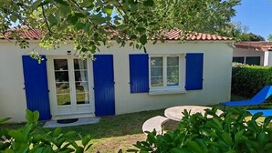 A small building with a tiled roof, a door with glass panels, and blue shutters.