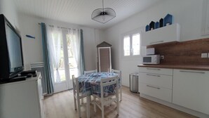 A kitchen with a dining table, white cabinets, a microwave, and a window with curtains.