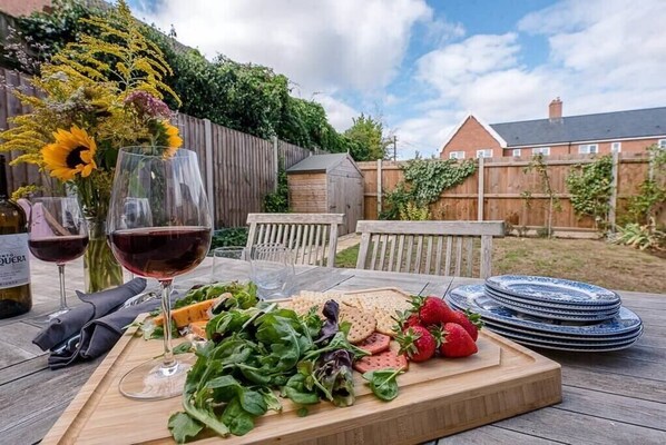 Une table en bois avec une salade, des crackers, des fraises et des verres à vin.