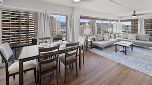 Una sala de estar moderna con comedor, ventanas amplias con vistas a la ciudad y un balcón.