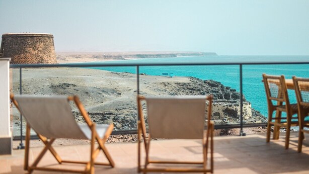 A balcony with two wooden chairs facing a rocky coastline and a clear view of the sea. - Ultimate Ocean View El Cotillo (El Cotillo)