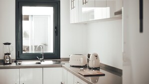 A modern kitchen with white cabinets, a window with a dark frame, a blender, a toaster, and a kettle on the counter. - Ultimate Ocean View El Cotillo (El Cotillo)