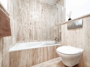 A modern bathroom with a marble wall, a freestanding bathtub, a toilet, and a wall-mounted bidet. - Ultimate Ocean View El Cotillo (El Cotillo)