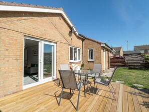 A patio with a table and chairs, a sliding glass door leading to a room, and a brick exterior. - 20 Southmead (Morpeth)