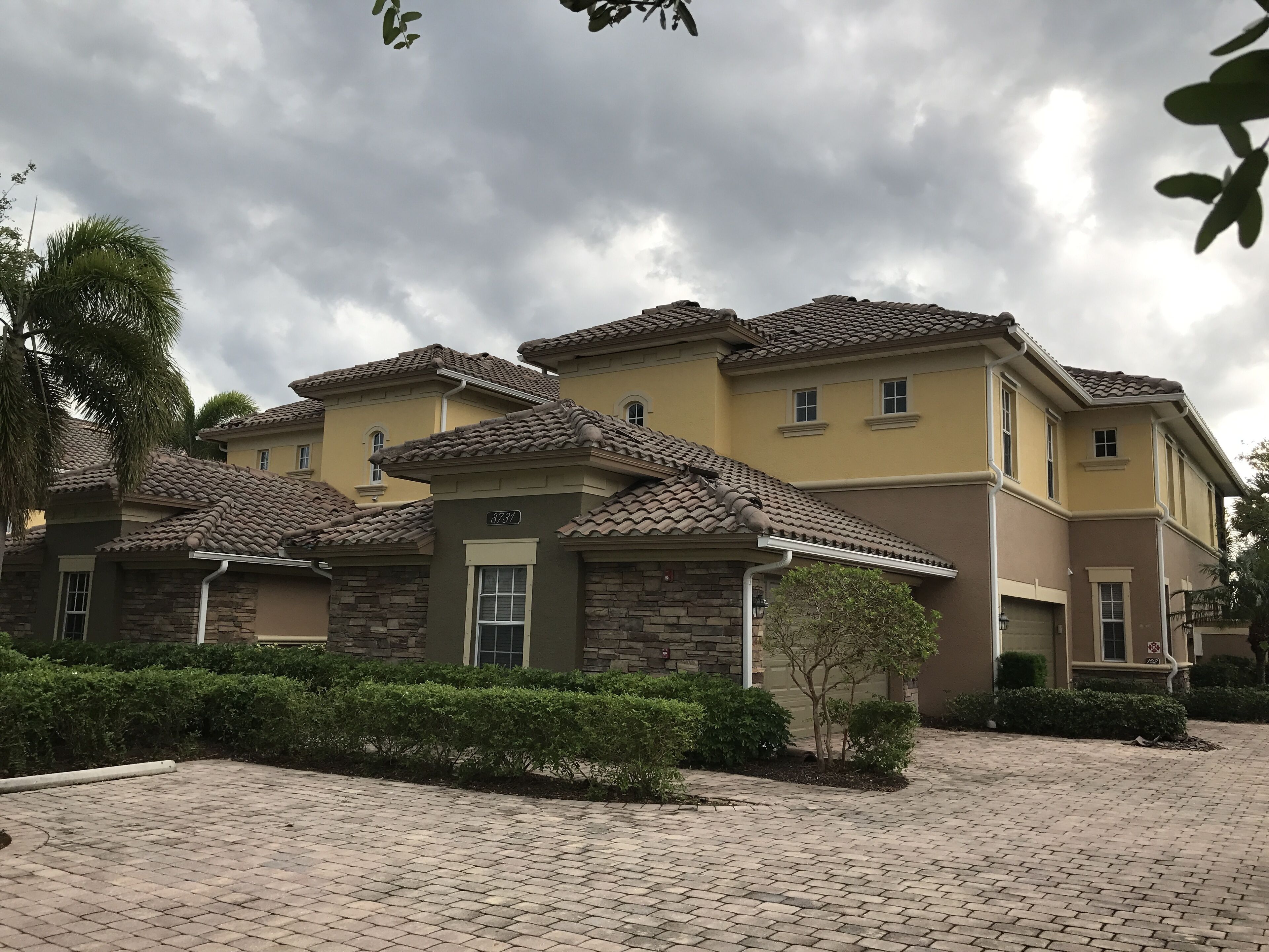 A residential building with a tiled roof, a number '8737' on the facade, and a paved driveway.