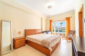 Ein Hotelzimmer mit Bett, Schreibtisch, Stuhl, Kleiderschrank und einem fenster mit Vorhängen.