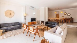 En moderne stue med sofa, lænestole, sofabord og fjernsyn.