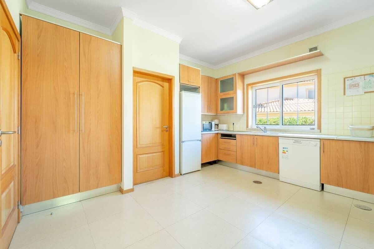 A kitchen with wooden cabinets, a refrigerator, a dishwasher, and a window.