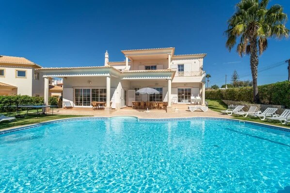Ein zweistöckiges Haus mit Schwimmbad davor.