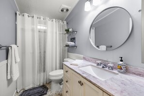 A bathroom with a toilet, a sink, a mirror, and a shower curtain. - Cheerful and Cozy Home 10 minutes from Downtown Bend…super close to the Old Mill (Bend)