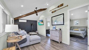 A spacious loft bedroom with a large bed, a desk, and a cozy seating area. - Cozy Beach Cottage with Sauna & Spacious Backyard just 5mins from the Beach (Port Rowan)